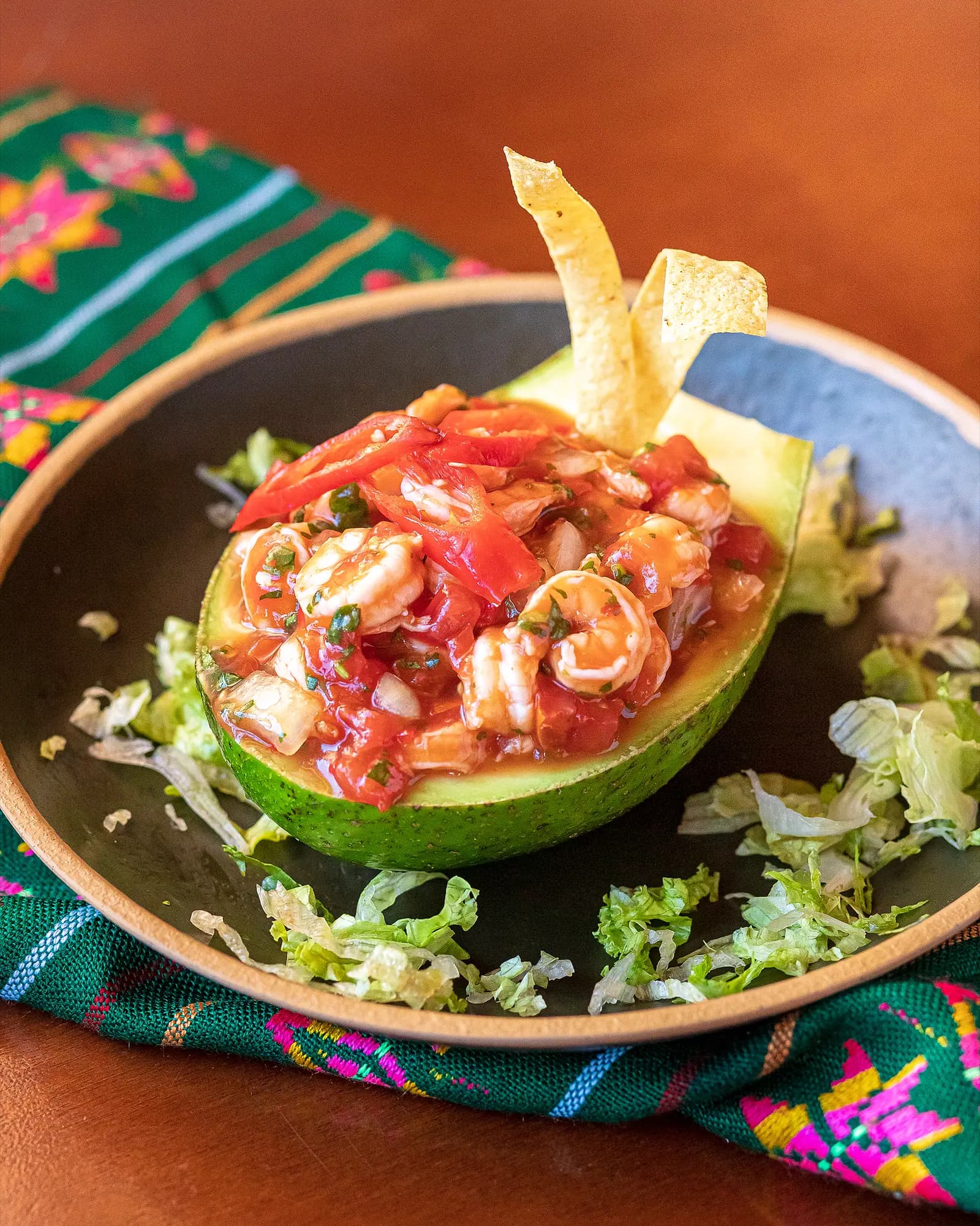 Ceviche de camarão servido na metade de um abacate com tiras de tortilla